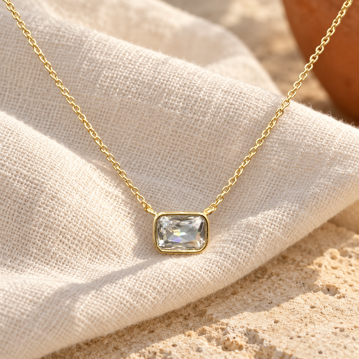 Brisa clear CZ necklace on warm ivory linen — digitally styled product image