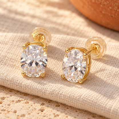 Clear oval prong-set CZ studs on sun-washed ivory linen — digitally styled product image