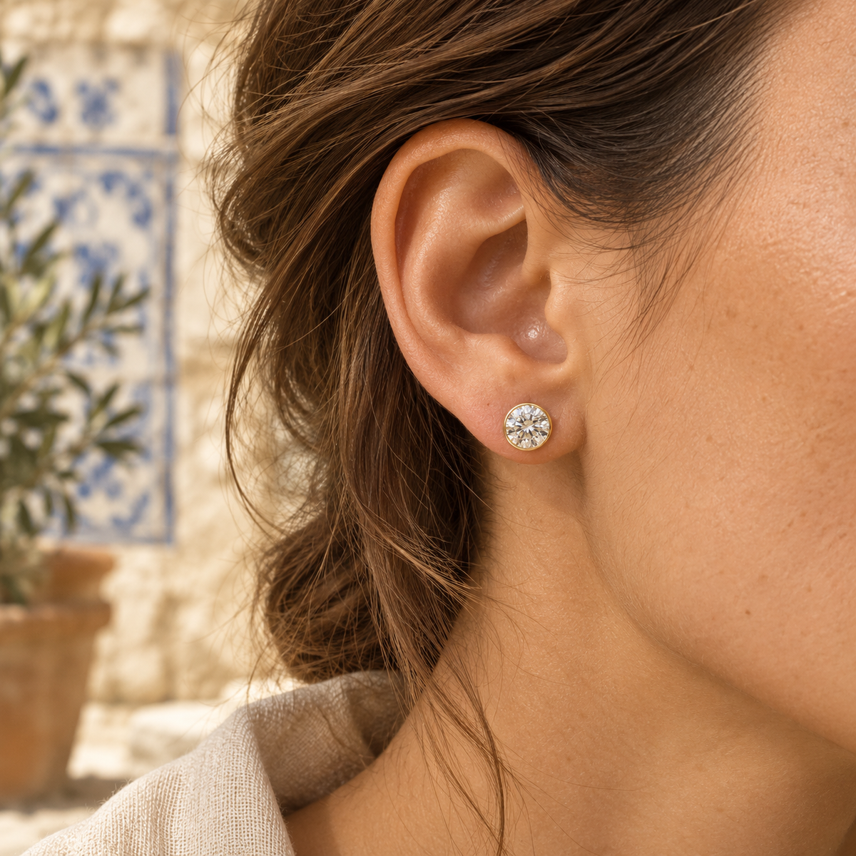 Halo bezel diamond stud — 6.5 mm diamond, 2 ct total per pair; AI-styled on-ear illustration, fit varies