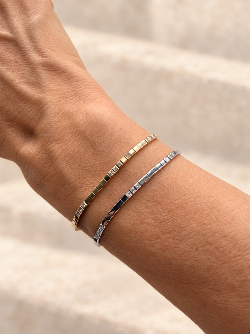 Raio bracelets in yellow and white gold worn on a wrist; retouched photograph.